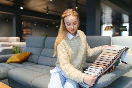 Portrait of young cheerful woman testing sofa in furniture store photo