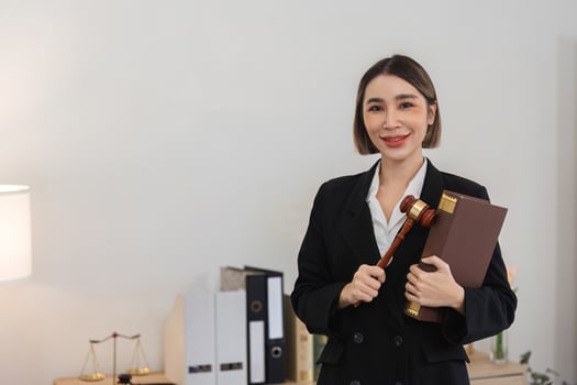 Confident Young Lawyer Holding Gavel and Legal Book in Modern Office Setting, Ready to Tackle Legal Challenges photo