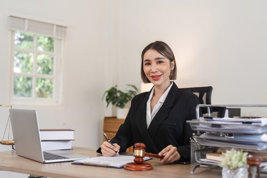 Confident Young Lawyer Working in Modern Office with Legal Documents and Gavel on Desk photo