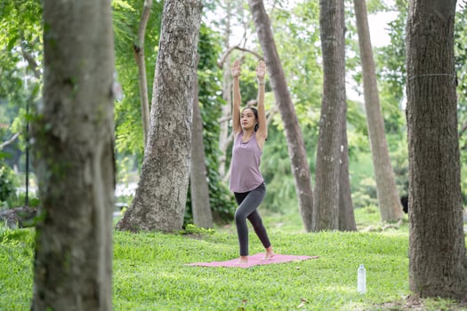 Young Healthy Woman Practicing Yoga Outdoors in a Lush Green Park Surrounded by Trees and Nature photo