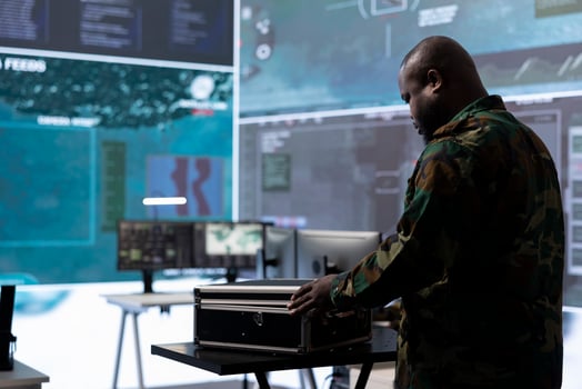 Military specialist in a command post uses advanced technology and high tech gear to gather intelligence from satellite cctv footage and computer surveillance systems to communicate information. photo