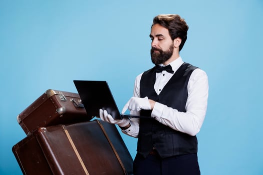 Hotel concierge with laptop in hand symbolizing role as porter or doorkeeper, leveraging modern technology to provide assistance. Bellhop checking online bookings or reservations on pc. photo