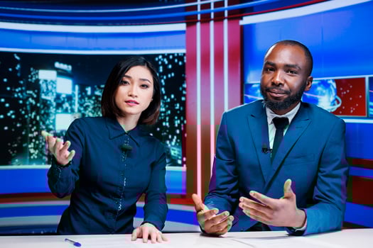 Night show hosts reviewing breaking news live on television program broadcast, working together to create interesting content for tv channel. Diverse team of journalists in newsroom. photo