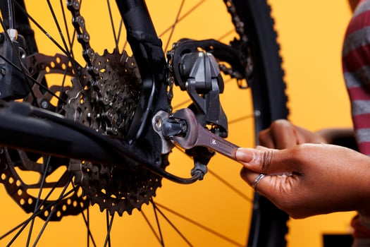 Detailed view of person grasping expert work tool for maintaining and repairing damaged bicycle. Close-up shot shows expertly and precisely adjusted parts being adjusted by african american hands. photo