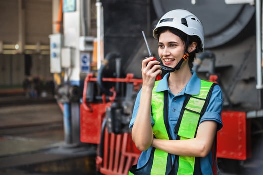 woman wearing a safety vest and a helmet is talking on a walkie talkie photo