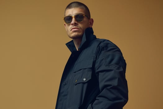 Navy Clothwear Jacket with Fashion Sunglasses Urban Lifestyle portrait in Light Tan Trendy Male Fashion Background photo