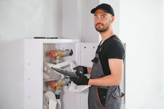 The worker installs or inspects Fire extinguisher and fire hose reel in building corridor photo
