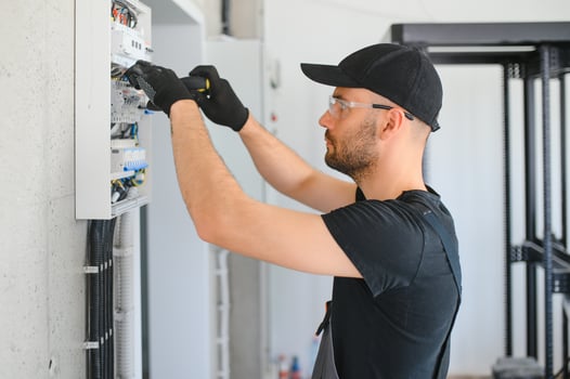 Male electrician working in a switchboard with fuses photo