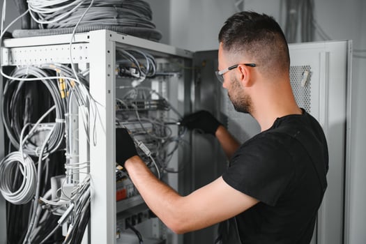 A technician works with server equipment in a data center. A man commutes wires in a server room photo
