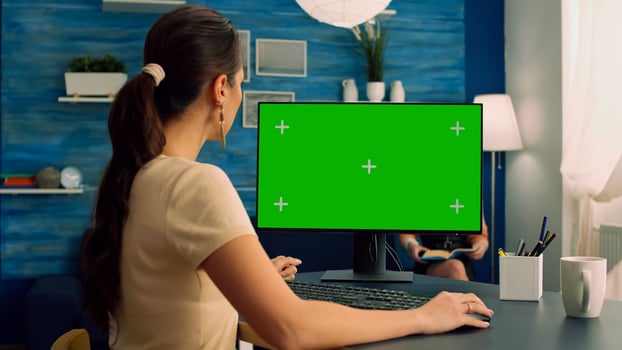 Caucasian female typing on professional computer with mock up green screen chroma key display sitting at modern office desk. Freelancer working at commerce project on isolated pc in living room photo
