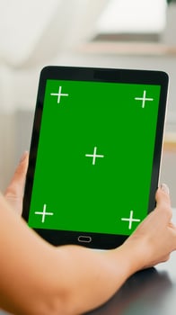 Freelancer woman holding tablet computer with mock up green screen chroma key display sitting on office room. Caucasian female browsing on internet for online project using isolated device photo