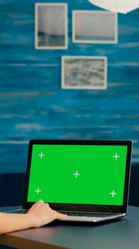 Freelancer using computer with mock up green screen chroma key for business company standing on desk table. Woman using isolated home office pc working at commerce project in home office photo
