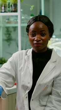 Pov of african woman sitting at desk table in pharmaceutical laboratory during online videocall meeting. Specialists team researching genetic mutation developing dna GMO biology test photo
