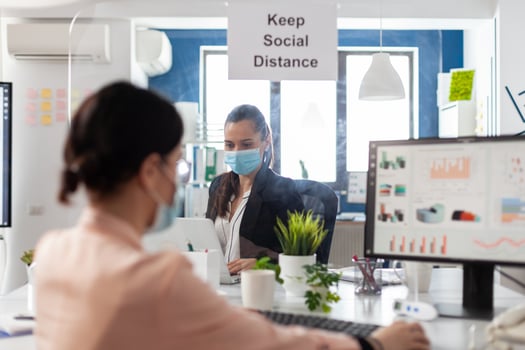 Businesswoman typing financial strategy on computer working at marketing presentation in startup corporate office. Business team wearing medical face mask to prevent infection with coronavirus photo