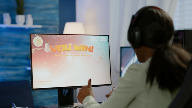 Excited black esport gamer celebrating championship victory, woman winning space shooter game. Pro cyber gaming online tournament live streaming championship using RGB powerful computer photo