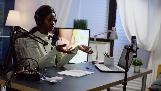 African influencer wearing headphones checking sound recording new podcast series at home studio for youtube channel. On-air online production internet broadcast show host streaming live content photo