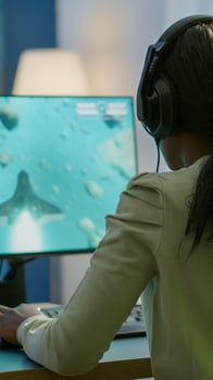 Competitive african gamer sitting on gaming chair, using headphone playing space shooter videogames on RGB powerful computer. Pro woman streaming cyber performing during online esports tournament photo