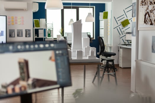 Table with scale foam model of skyscraper in empty architectural office used for urban development and architecture design. Workstation with 3D render blueprints of real estate buildings. photo