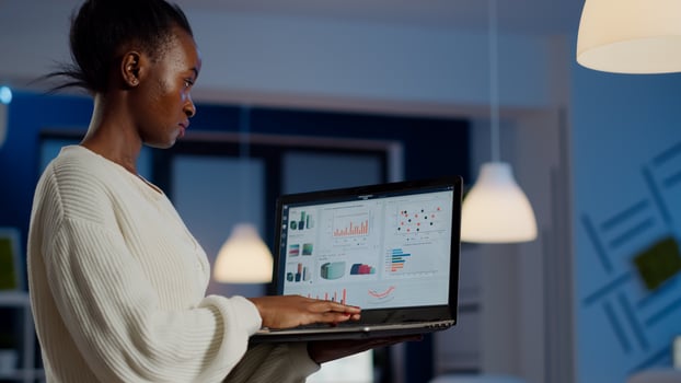 African freelancer typing on laptop late at night standing in start up business office late at night working. Busy employee using modern technology network wireless doing overtime for job searching photo