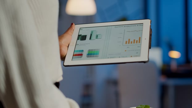 Close up of black entrepreneur analysing financial reports zoom in standing in start up office late night holding laptop. African employee working checking statistics overworking writing, searching. photo