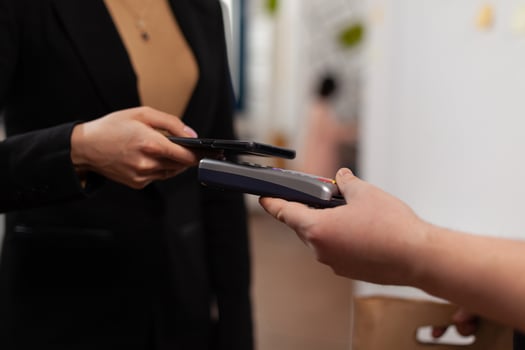 Close up of business woman paying delivery guy from frood service, using smartphone nfc technology. Entrepreneur recieving tasty takeaway lunch in paper bag. photo