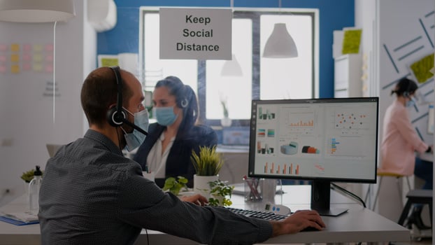Close up of businessman talking with coworker into microphone about business meeting wearing protective face mask. Professional team wearing face masks to prevent infection with coronavirus photo