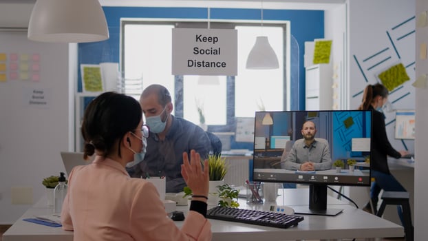 Businesswoman having online videocall meeting, disscusing about communication project in new normal company office. Team wearing face masks mantain social distance during coronavirus pandemic photo