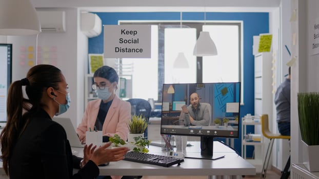 Coworkers wearing medical face masks to prevent infection with coronavirus while working in office company. Business woman talking with her team during online communication meeting photo