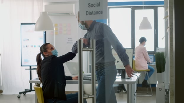 Caucasian male greeting his collegue with elbow to avoid covid19 infection. Workers working in new normal company office keeping social distancing during coronavirus global pandemic photo