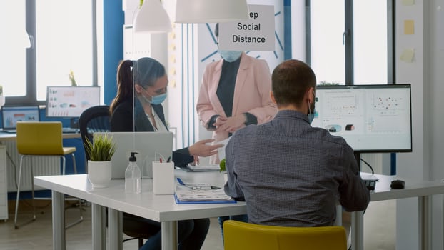 Business womens with medical face masks looking on financial graphs standing at desk table in startup office. Coworkers keeping social distancing to avoid infection with coronavirus during epidemic photo
