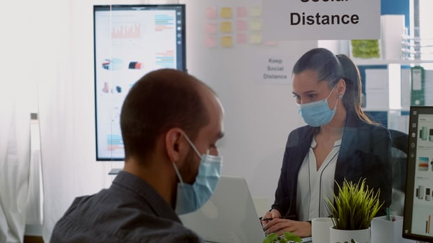 Coworkers working at business ideas wearing protection face mask to avoid infection with coronavirus during global epidemic. Coworkers keeping social distancing while typing on computer checking reports photo