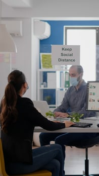 Businessman with face mask touching elbow with his collegue to avoid infection with coronavirus. Coworkers mantain social distancing while working on communication company project photo
