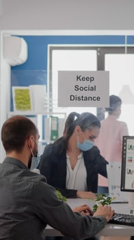 Businesspeople analysing financial graphics while working after lockdown in new business office wearing protective face mask to prevent infection with coronavirus. Team mantain social distancing photo
