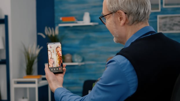 Senior man having call online talk with nephew using smartphone sitting in living room. Retired old person using modern internet online tech to connect with grandparents photo