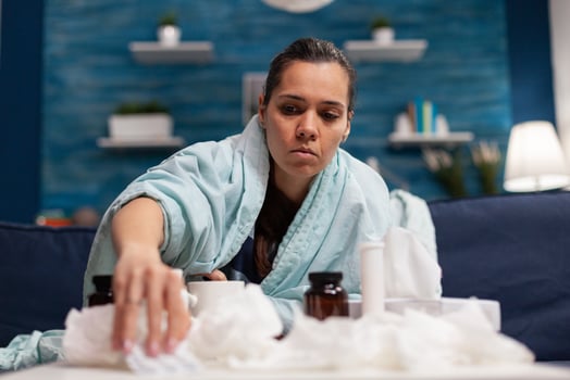 Sick woman taking medicine for seasonal virus wrapped in blanket holding pills. Caucasian young person treating disease with medical treatment for covid 19 symptoms temperature pain photo