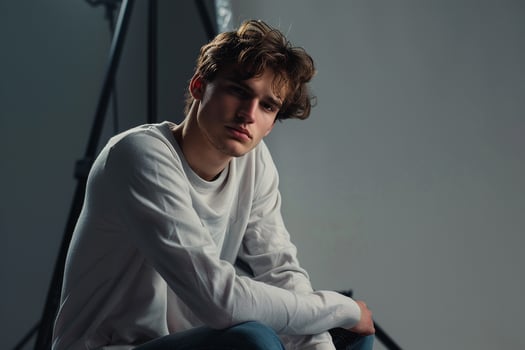 Handsome male in a long sleeve shirt cloud grey backdrop relaxed portrait modern fashion stylish look photo