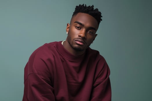 Fashionable male fashion model in a maroon sweatshirtmale dress shot withsage green Males backgroundhighlightingfashion and lifestyle portrait with a stylish twist photo