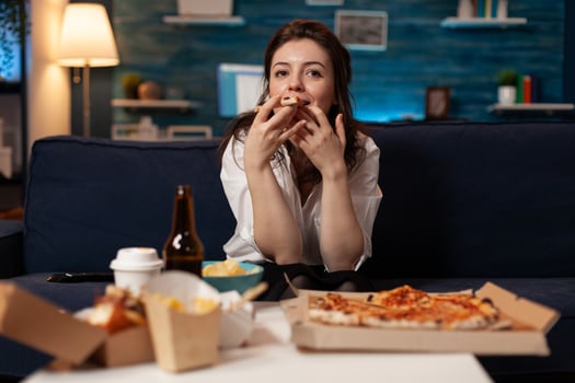 Portrait of woman watching comedy movie eating tasty delivery pizza slice relaxing on sofa in living room at night. Caucasian female enjoying takeaway food home delivered. Fastfood meal order photo