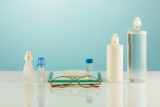 Oftalmology concept with eyeglasses, contact lenses, eye drops, clean solutions photo