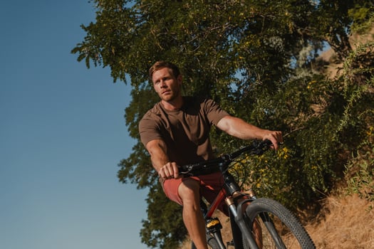 Handsome young man riding bicycle by the scenic road outdoors photo