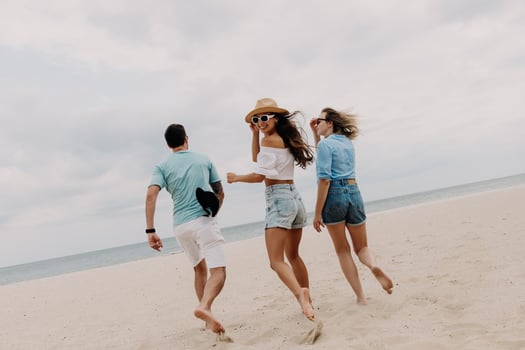 Three happy young friends spending carefree time while running by the beach together photo