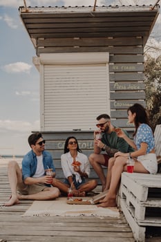 Group of happy friends enjoying pizza and drinks while relaxing near the beach cafe together photo
