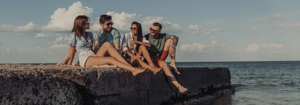Group of happy young friends enjoying beer while spending carefree time seaside together photo