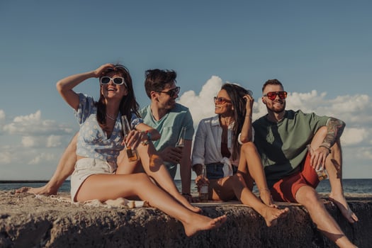 Group of happy young friends enjoying beer while spending carefree time seaside together photo