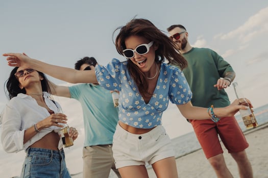 Group of beautiful young people enjoying beer and dancing while having fun on the beach together photo