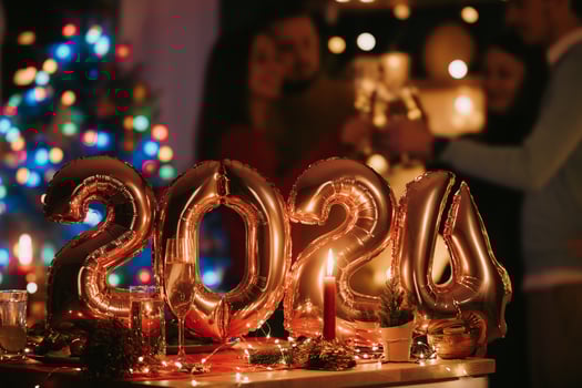Happy young people celebrating New Year with golden balloons in shape of number 2024 on foreground photo