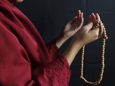 hand of muslim woman wearing mukena hold prayer beads photo