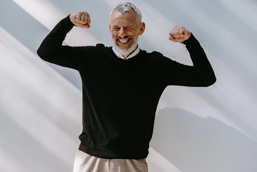 Portrait of happy senior man in smart casual wear looking excited while gesturing against the wall photo
