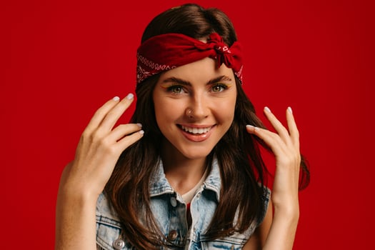 Happy young hipster woman wearing bandana and smiling on red background photo