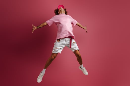 Full length of young fashionable man jumping against red background photo